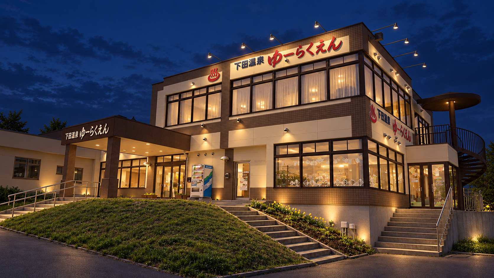 同じ茶色とアイボリーの外観を、入口の灯りと暖色の壁面照明でライトアップした夜の外観案
